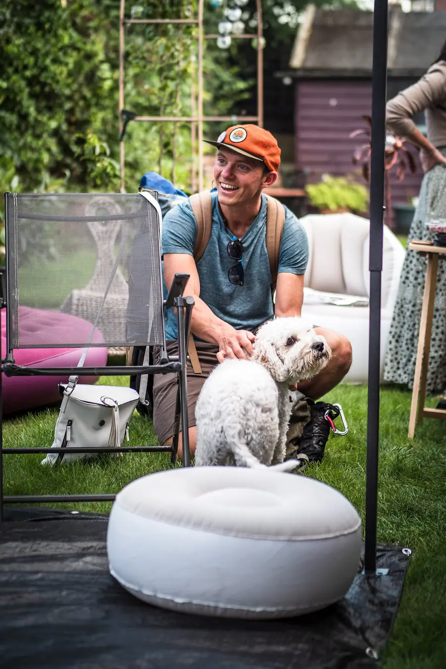 Frankie stroking a curly-haired dog in a garden.